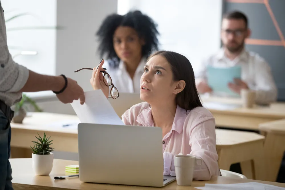 A woman sitting down, arguing with someone while holding her glasses.