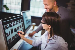 A man and a woman are taking a look at a desktop.