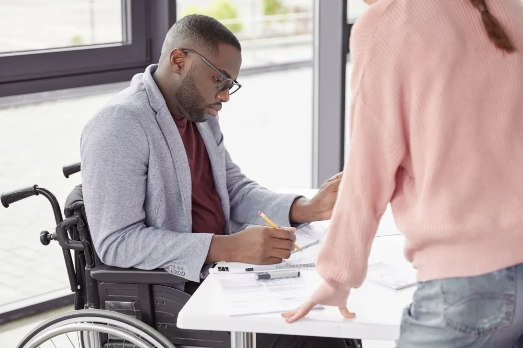 A man in a wheelchair is signing a document.