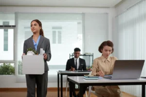 A woman walking away carrying a box of her belongings.
