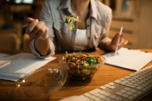 A woman eating at his desk.
