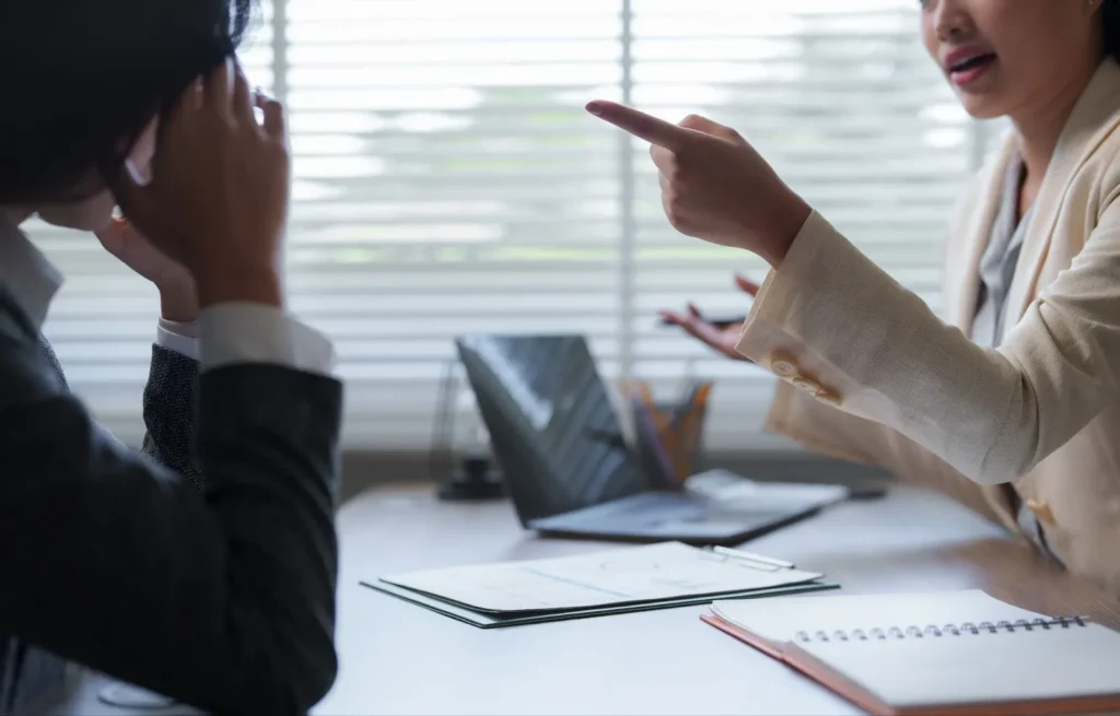 A woman is pointing at a person at the workplace.