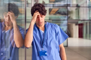 A medical worker sitting and holding his head